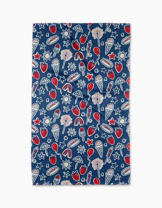 Decorative blue tea towel with white and red summer decor. Decor includes strawberries, ice cream, popsicles, sun, stars, rainbows, hotdogs, fireworks, balloons, sparklers, and beach umbrellas. On a white background.