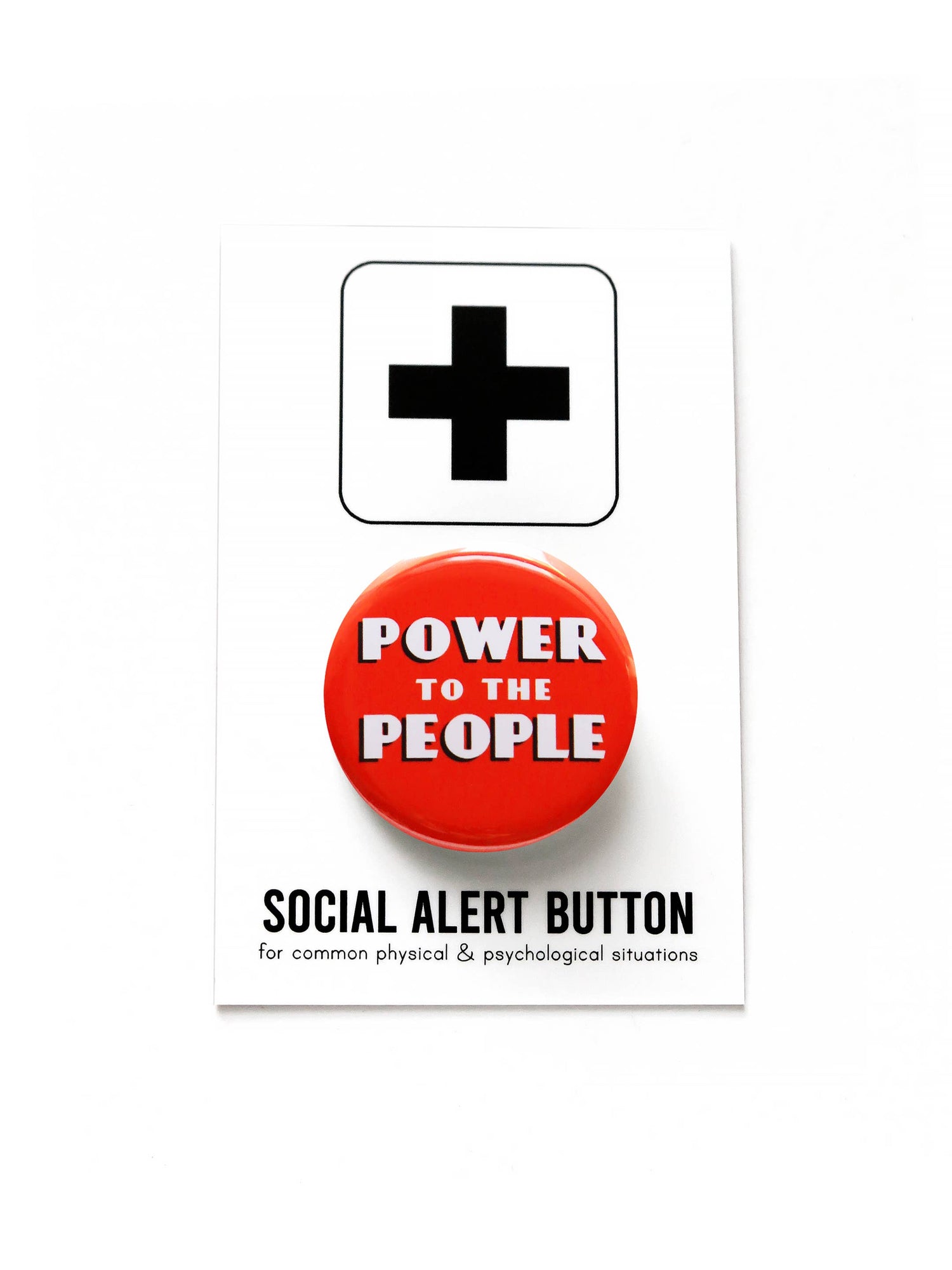 A red button with white text stating ‘Power to the people’ on black and white ‘Social alert button, for common physical & psychological situations’ packaging on a white background.