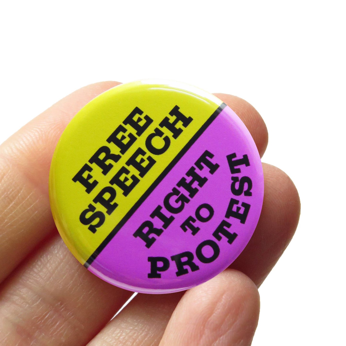 Bright green and purple button badge with 'Free Speech Right to Protest' text held in a hand against a white background.