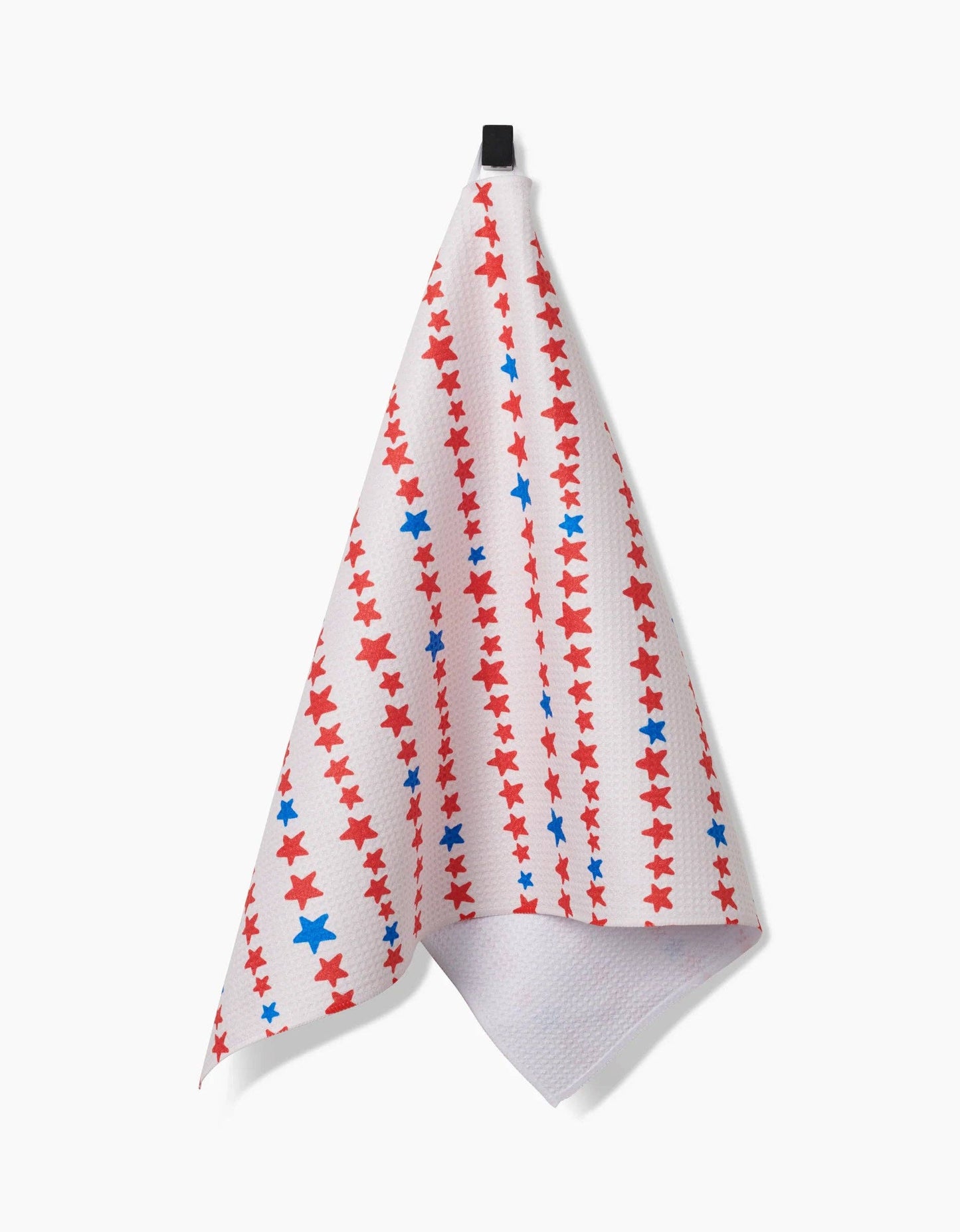 Decorative white tea towel with red and blue stars arranged in a stripe pattern hanging from a hook on a white background. 