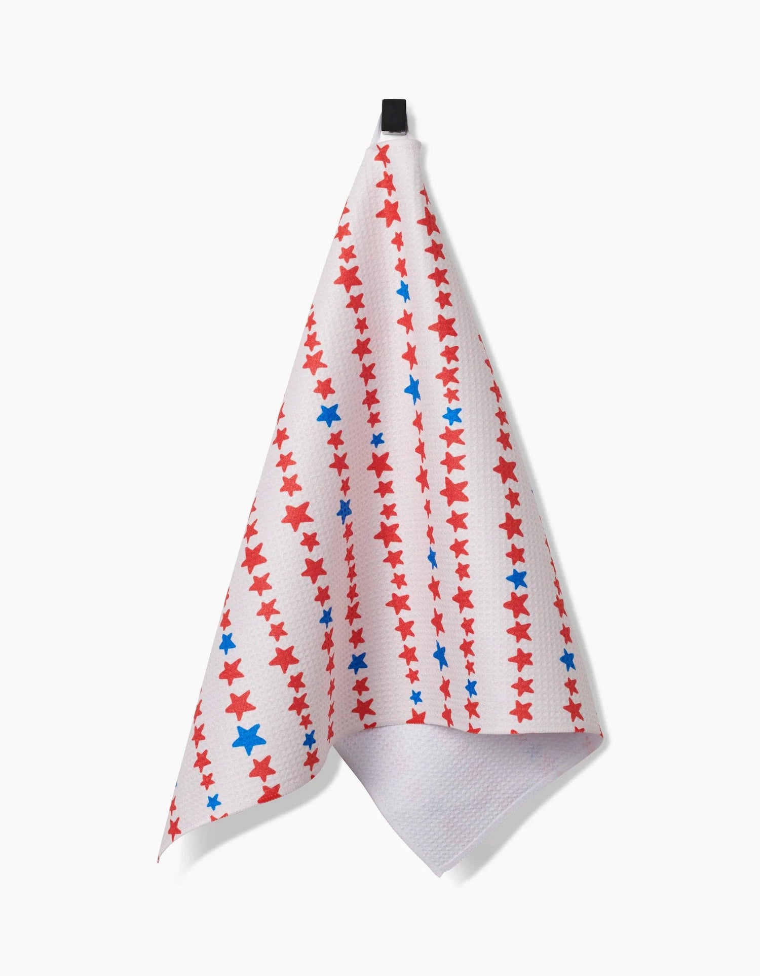 Decorative white tea towel with red and blue stars arranged in a stripe pattern hanging from a hook on a white background. 