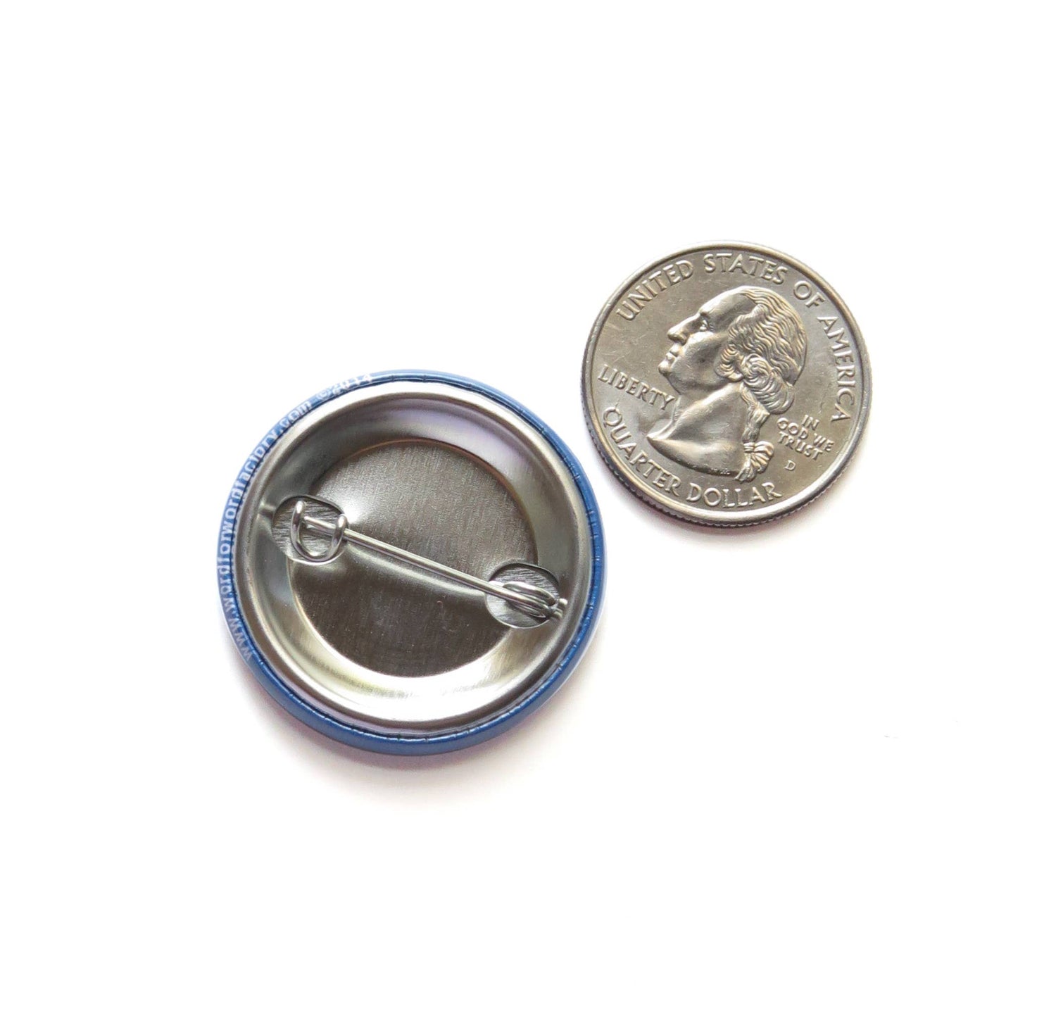 Back of button with metal pin next to US quarter coin for size comparison. On white background. 