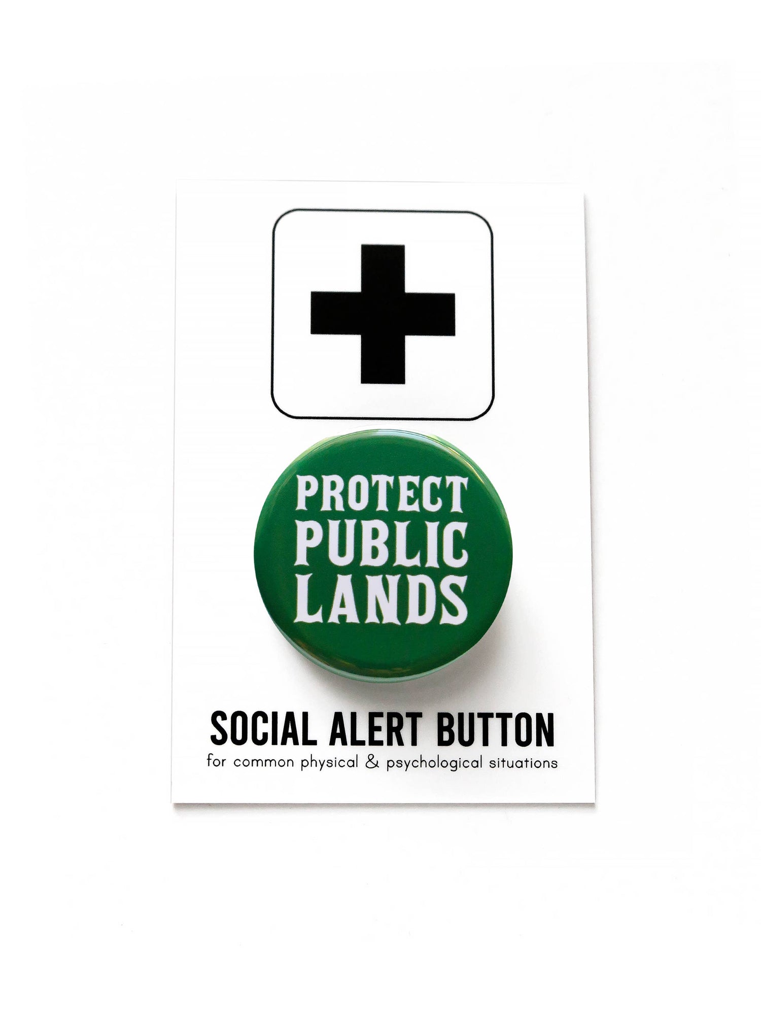 Green button with 'Protect Public Lands' text on black and white ‘Social alert button =, for common physical &psychological situations’ packaging on a white background