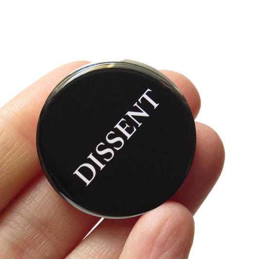 Black button with 'DISSENT' text held in a hand against a white background
