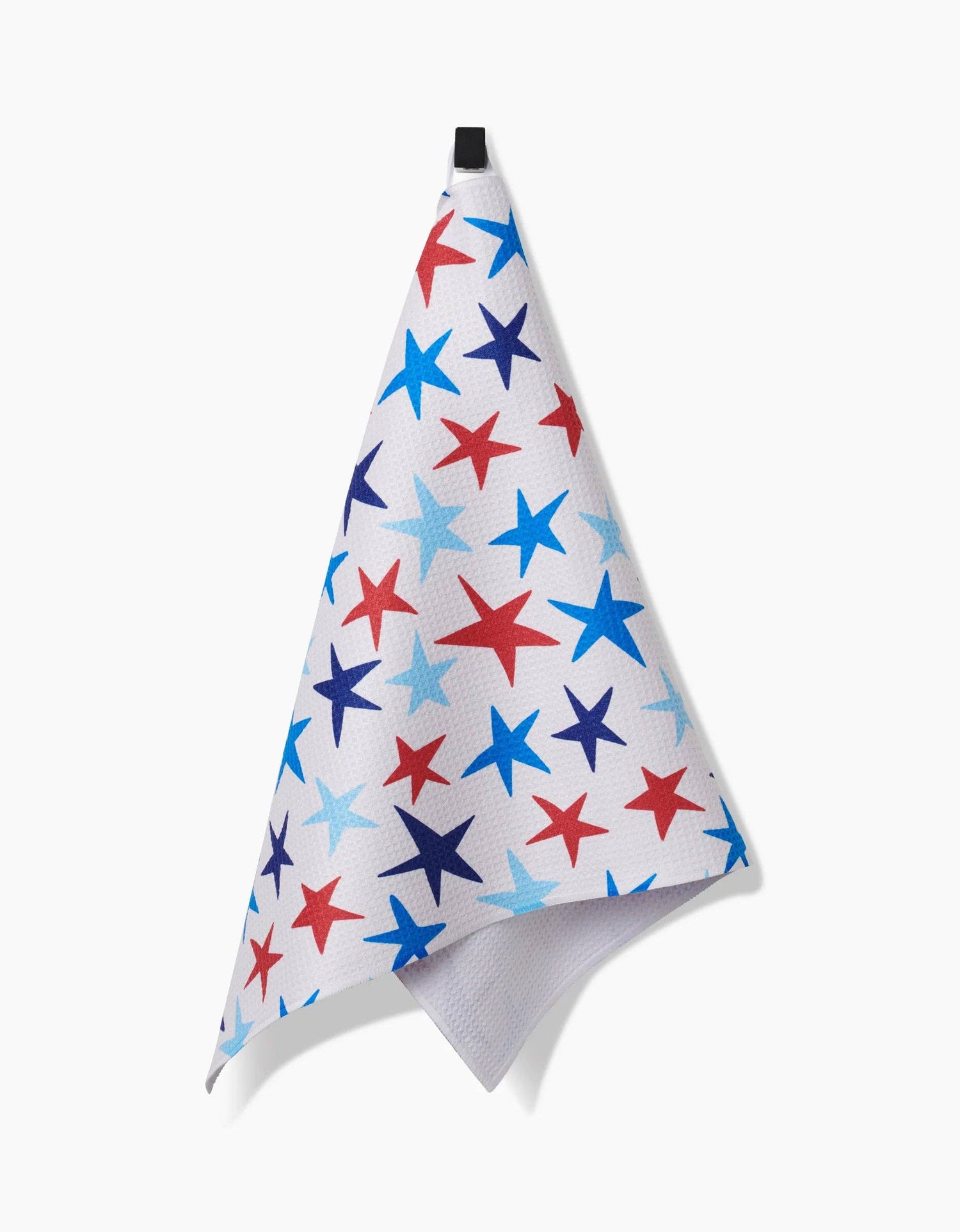 A decorative white tea towel with red, dark blue, and light blue stars of various sizes hanging from a hook on a white background. 