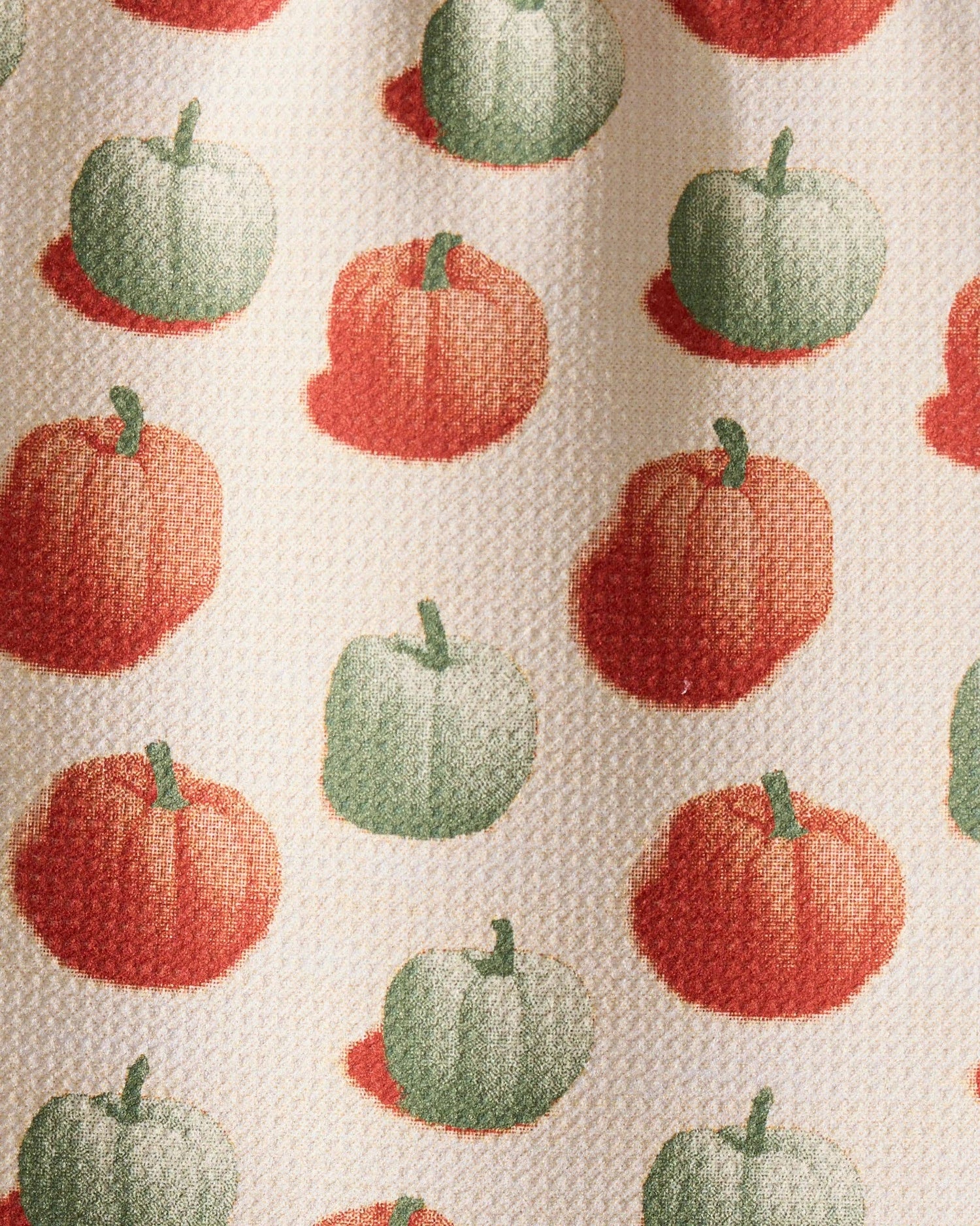 Close of up a white decorative tea towel with orange and green pumpkins. 