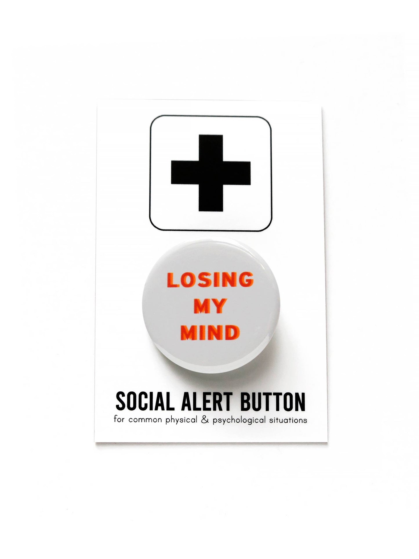 White button with ‘Losing my mind’ words on a white and black ‘Social Alert Button for common physical & psychological situations’ packaging. 