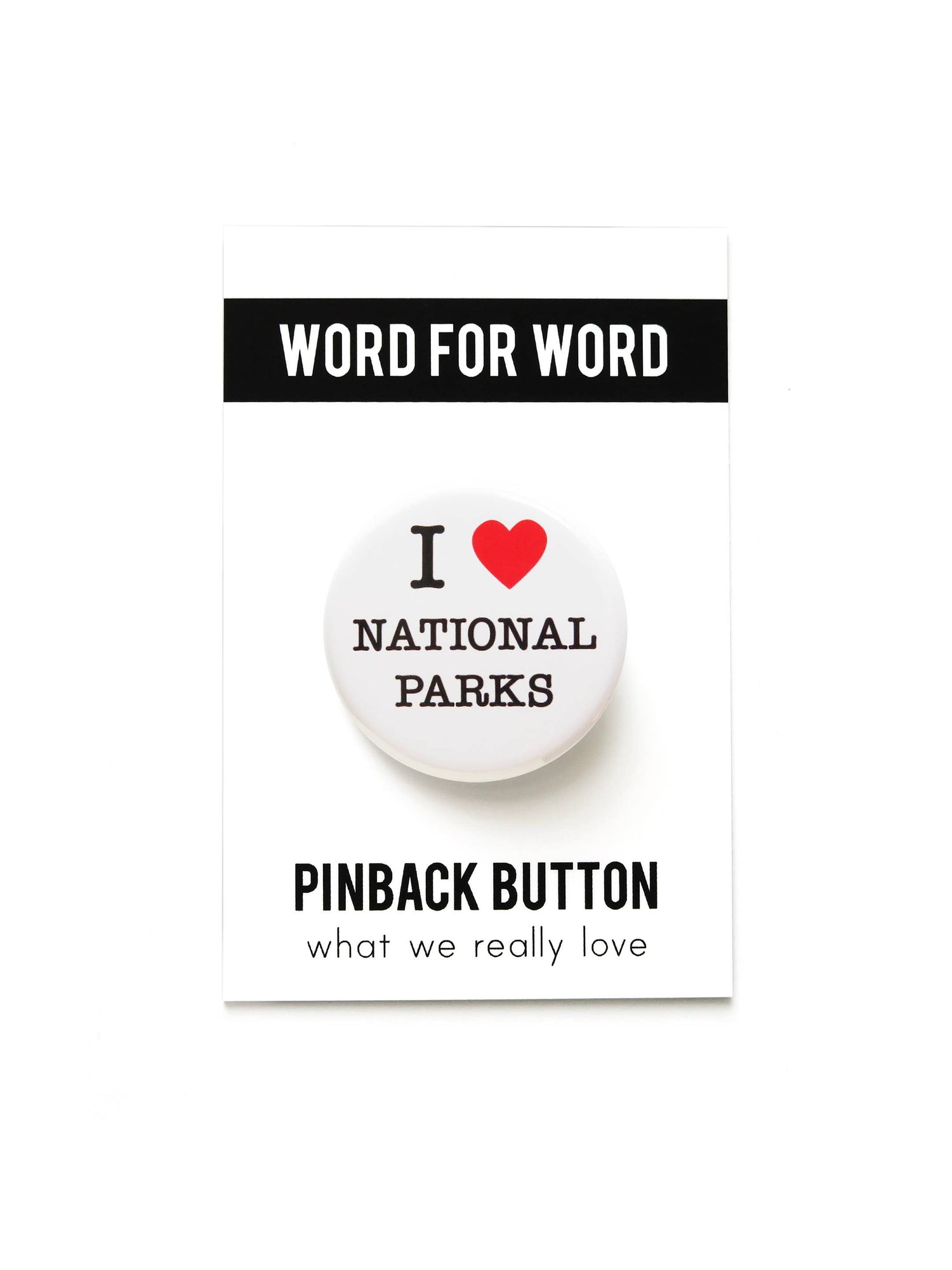 White button with ‘I heart national parks’ text on black and white ‘Word for word, Pinback button what we really love’ packaging on a white background.