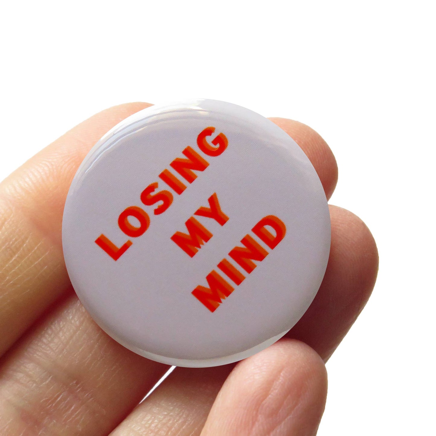 Button with 'Losing my mind' text held in a hand against a white background