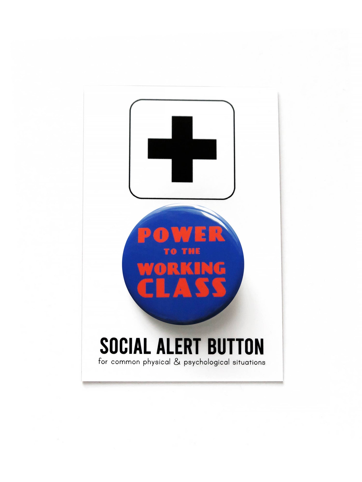 Blue button with red 'Power to the Working Class' text on black and white ‘Social alert button, for common physical & psychological situations’ packaging. On top of a white background.