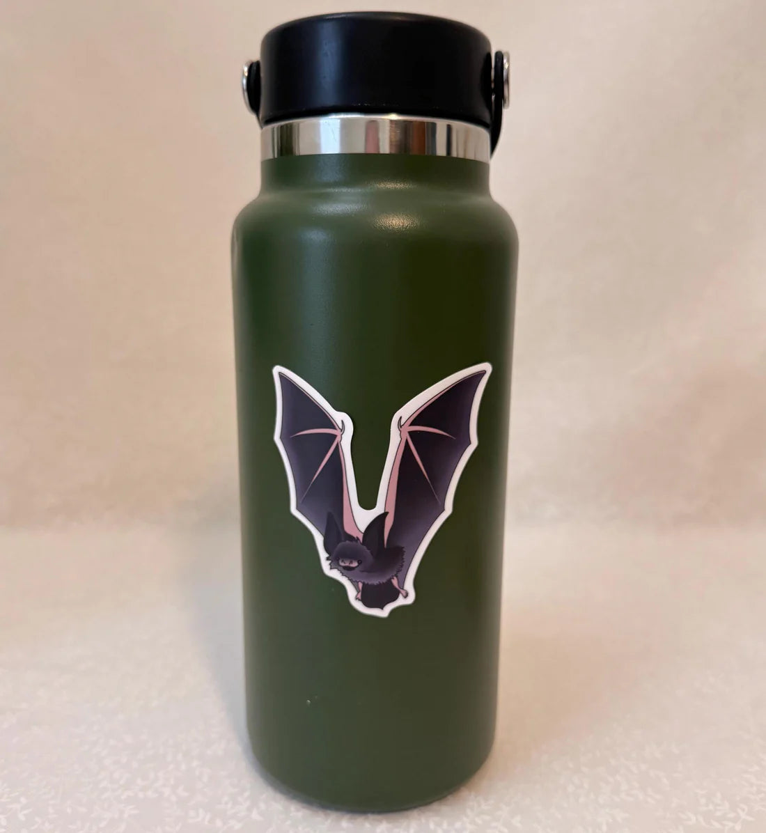 Green water bottle with a bat design sticker on it.
