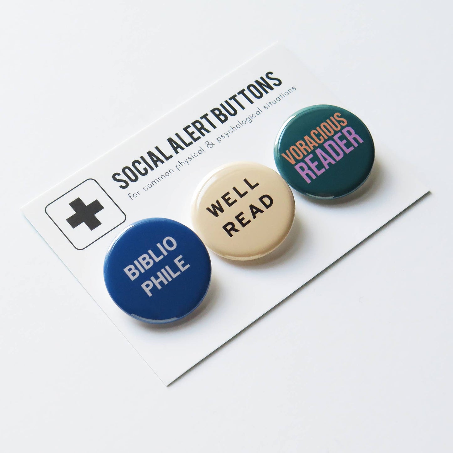 Three buttons on white packaging. The first blue button says ‘Bibliophile”, the second white button says ‘Well read’, and the third button says ‘Voracious reader’