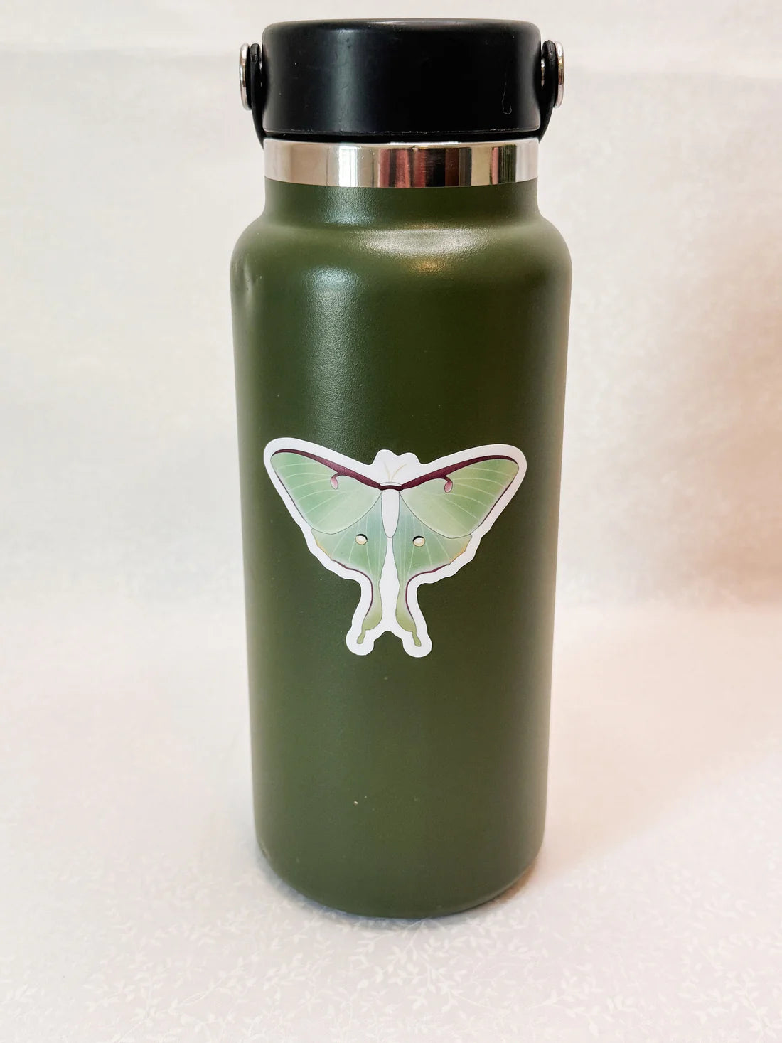 Green water bottle with a Luna moth sticker on it.
