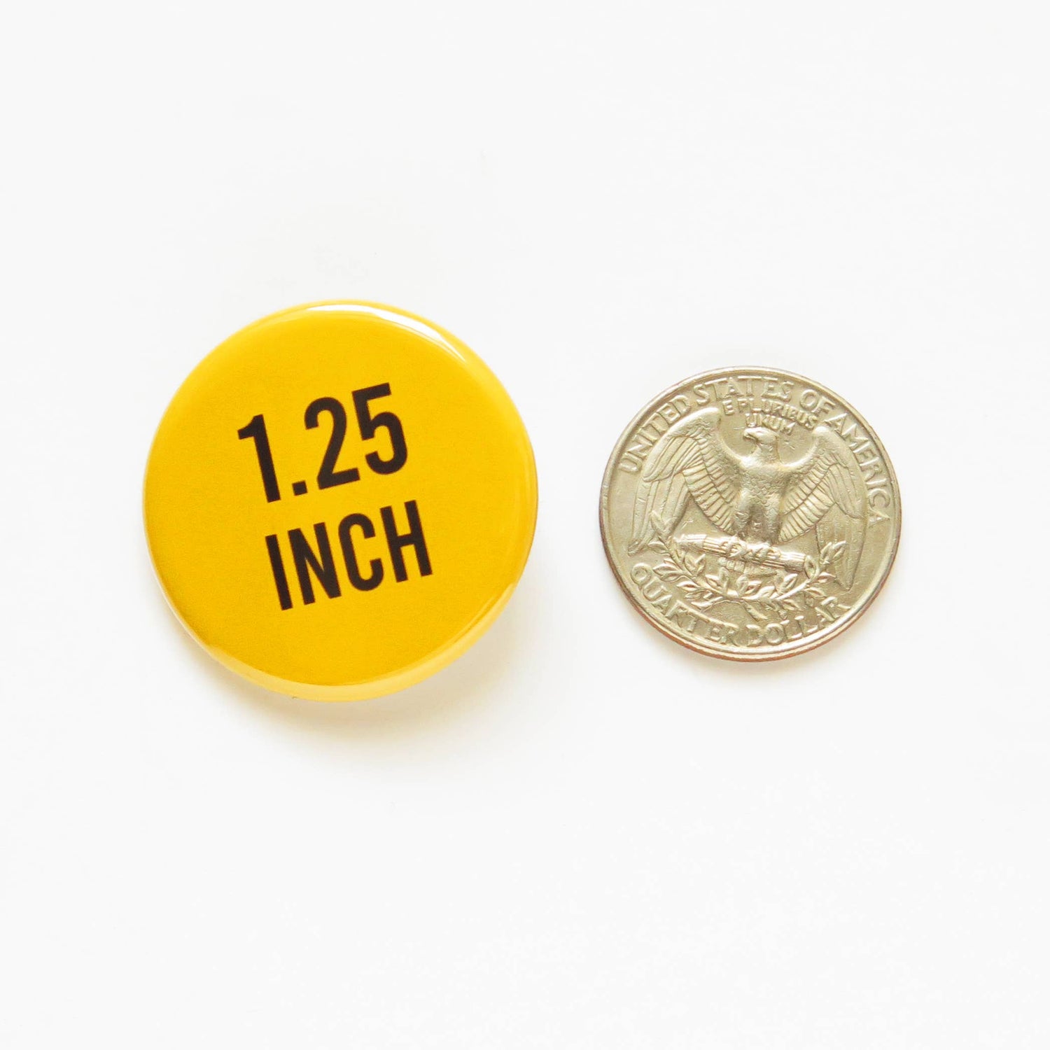 Yellow button with '1.25 INCH' text next to a U.S. quarter on a white background showing size comparison. 