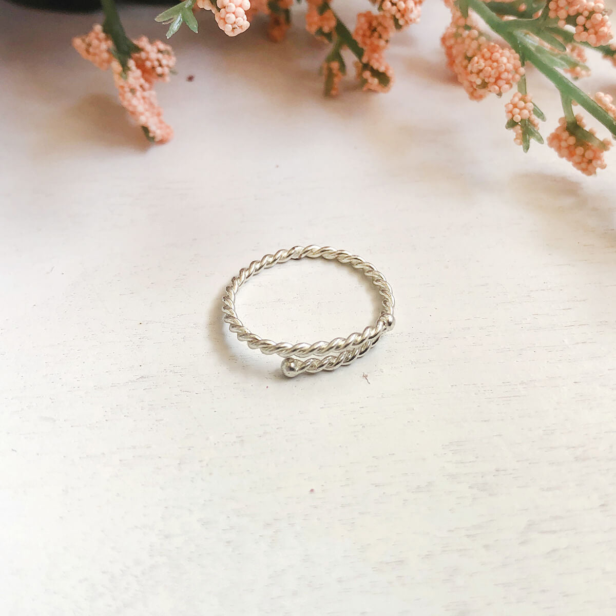 Image of the silver Twisted Stacking Ring, next to flowers.