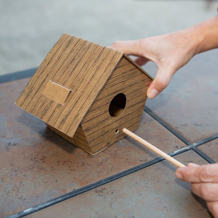 Photo of a model finishing building the DIY Log Cabin Bird House.