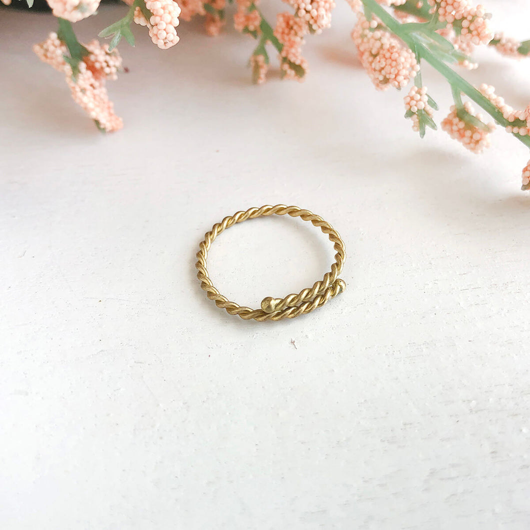 Photo of the gold Twisted Stacking Ring, next to flowers.