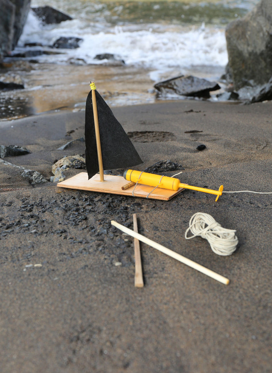 Environmental photo of a built Huckleberry “Make Your Own” Motor Boat, next to water.