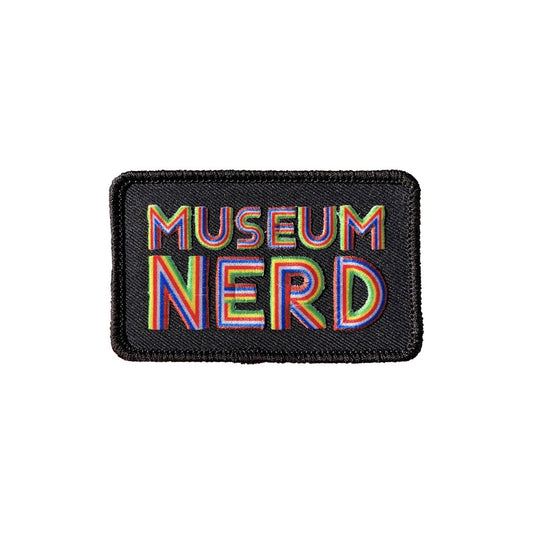 Image of the black Museum Nerd embroidered patch with rainbow colored text.