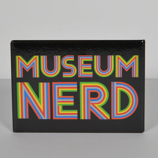 Photo of the black Museum Nerd magnet with rainbow colored font.