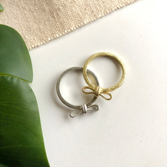 Image of the gold and silver “Wrapped Bow” Rings, next to each other.