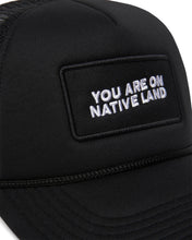 Load image into Gallery viewer, Detail photo of “You Are On Native Land” trucker hat in black embroidery.
