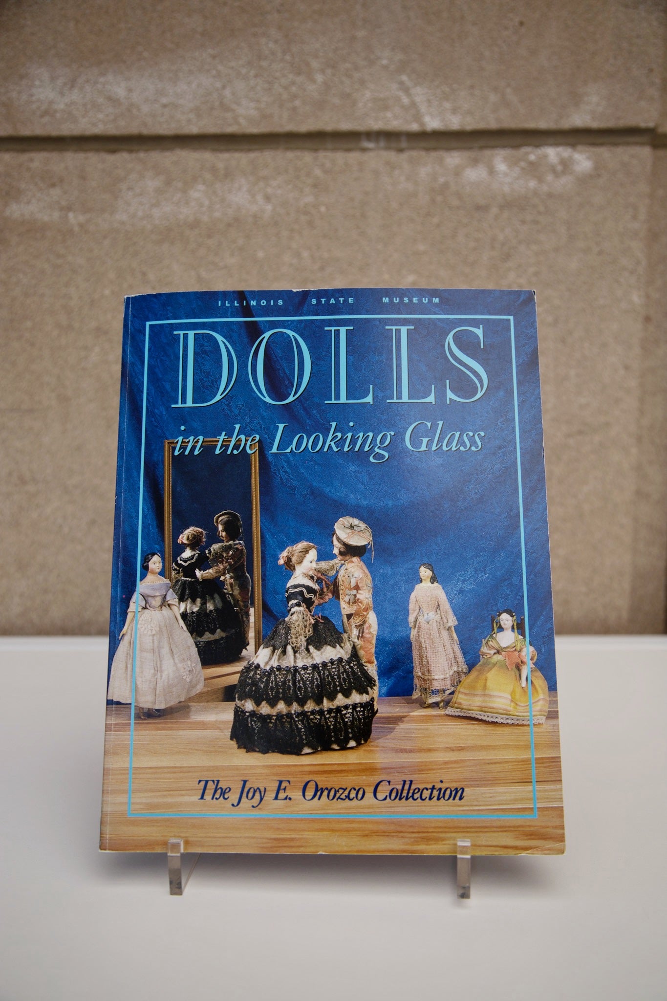Photo of the cover of the book “Dolls in the Looking Glass: The Joy E. Orozco Collection”
