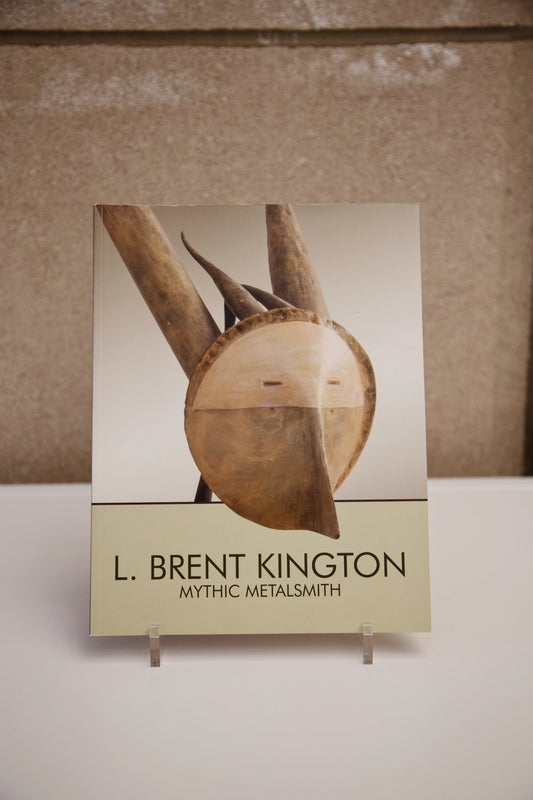 The book “L. Brent Kington: Mythic Metalsmith” on a book stand.